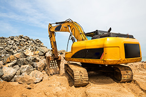 Track hoe lifting boulders