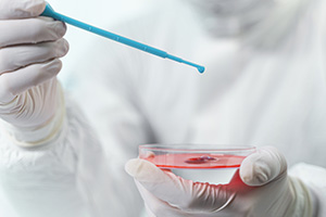 Biologist dropping sample into petri dish