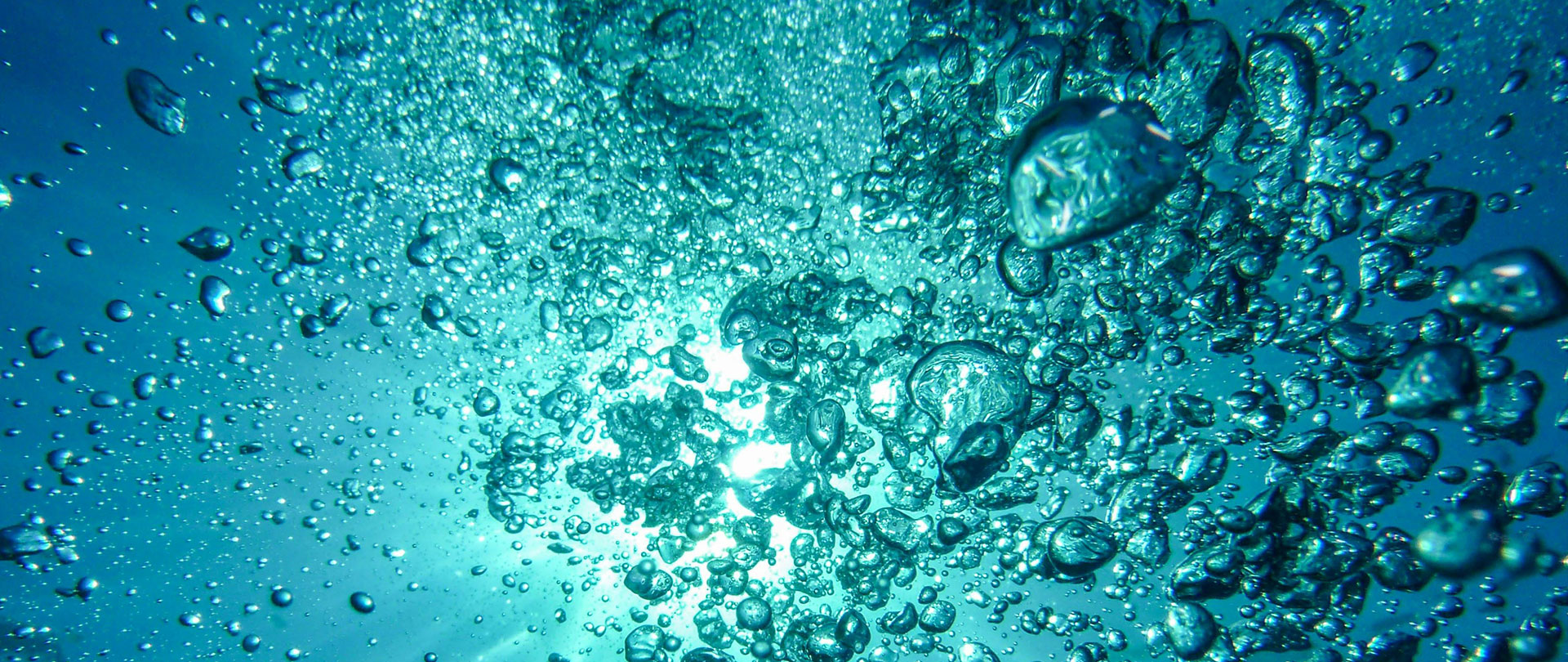 Underwater shot showing bubbles rising through the water, with light filtering from above and creating a serene blue atmosphere.