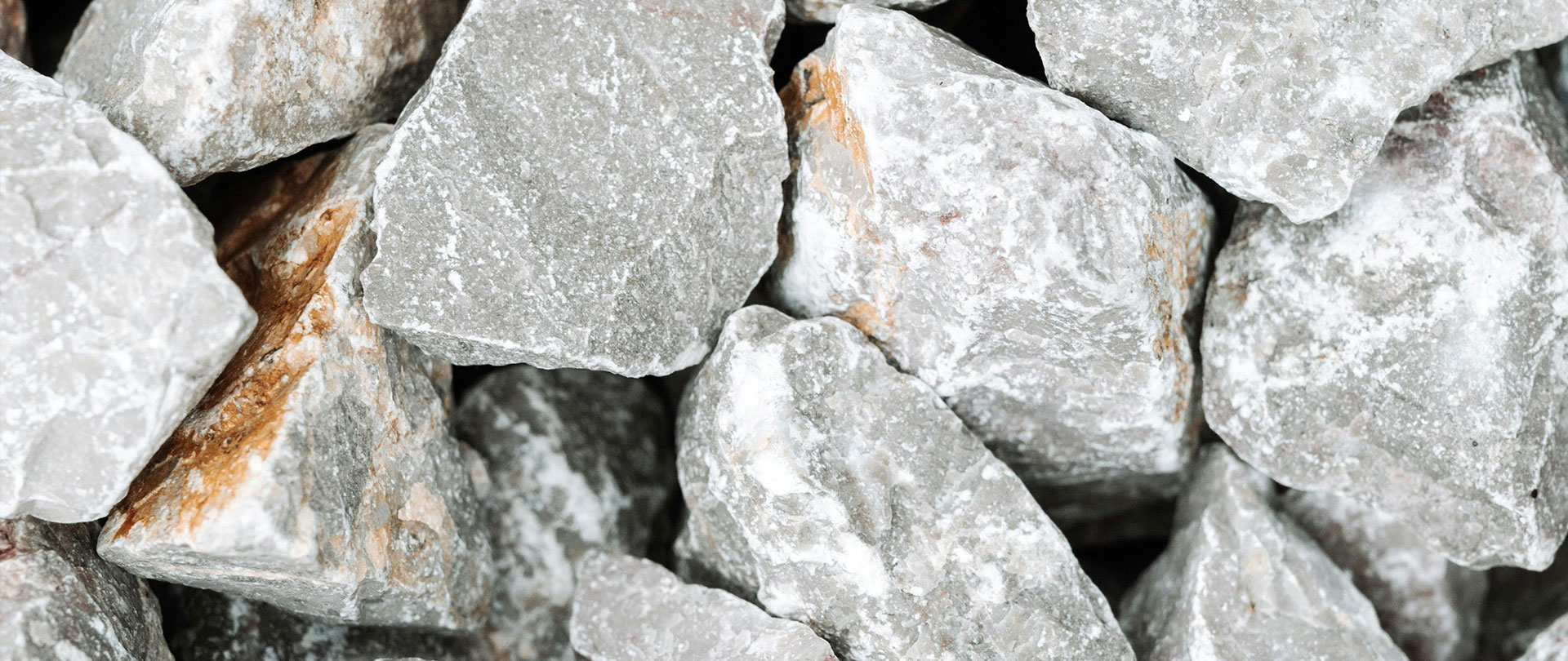 Close-up of rough, gray stones with visible textures and mineral deposits, forming an abstract natural pattern.