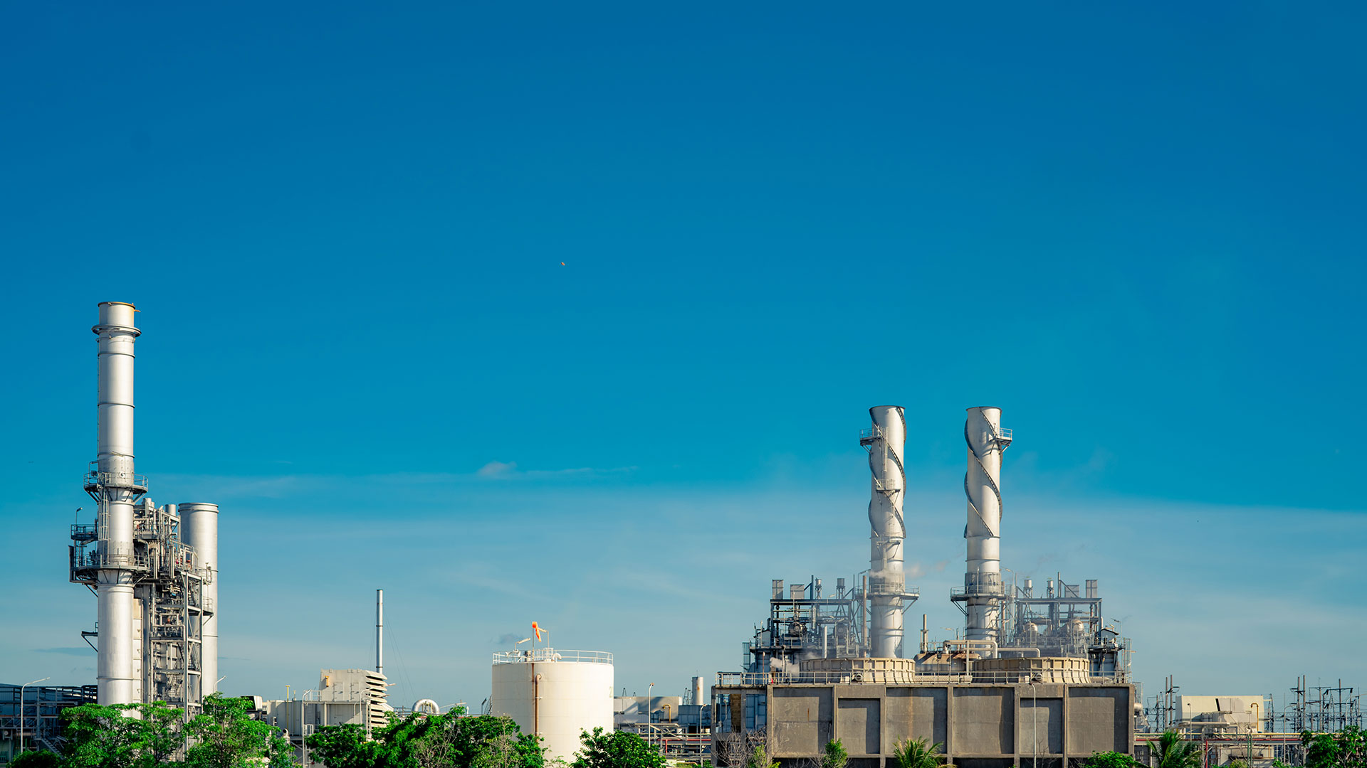 Installation industrielle avec des cheminées émettant des émissions visibles minimales contre un ciel bleu.