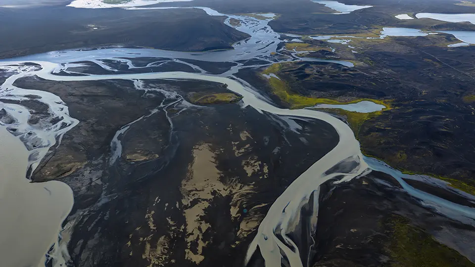 Vista aérea de un sistema fluvial con riachuelos y el paisaje geológico circundante, que ilustra los procesos ambientales y geocíclicos.