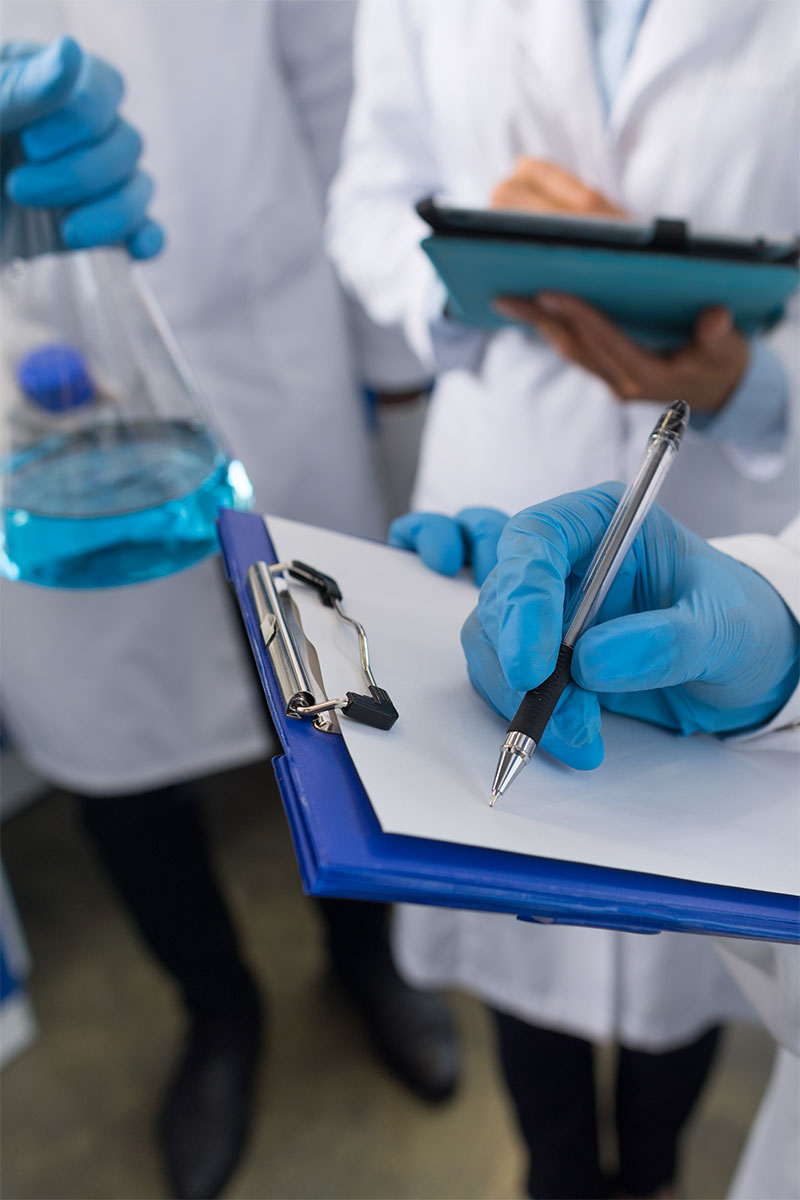 A pipette releasing a droplet of liquid into a row of test tubes in a laboratory setting.