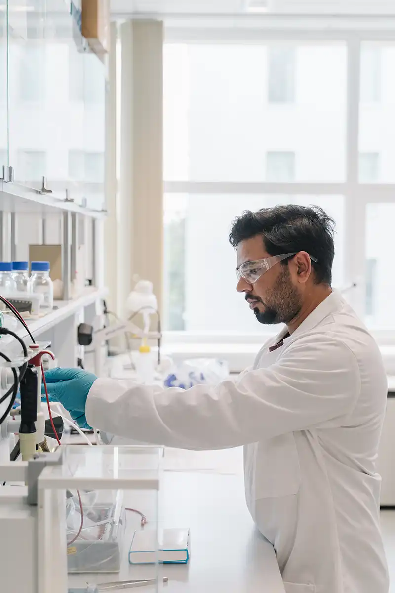 Una pipeta que libera una gota de líquido en una fila de tubos de ensayo en un laboratorio.