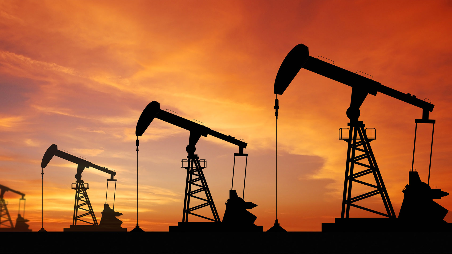 Silhouette des pompes à pétrole au coucher du soleil, représentant la production d'énergie dans l'industrie pétrolière